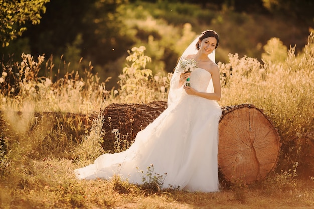 Невеста, опираясь на большой деревянный ствол