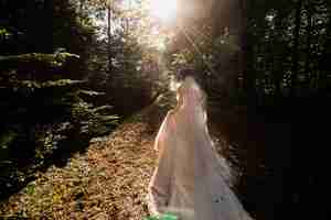 Free photo bride in the long wedding dress goes on the forest path