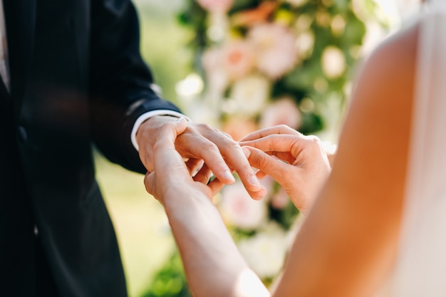 Bride puts wedding ring on groom's finger. No face