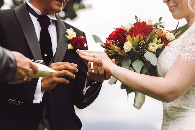 Bride puts wedding ring on groom's finger