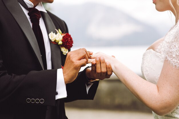 Bride puts wedding ring on groom's finger
