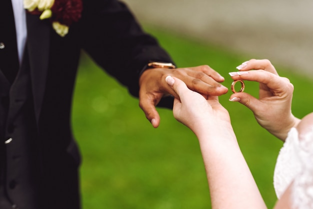 Bride puts wedding ring on groom's finger