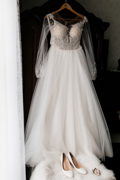 Bride's dress is hanging and foreground bride's shoes are on a fur poof