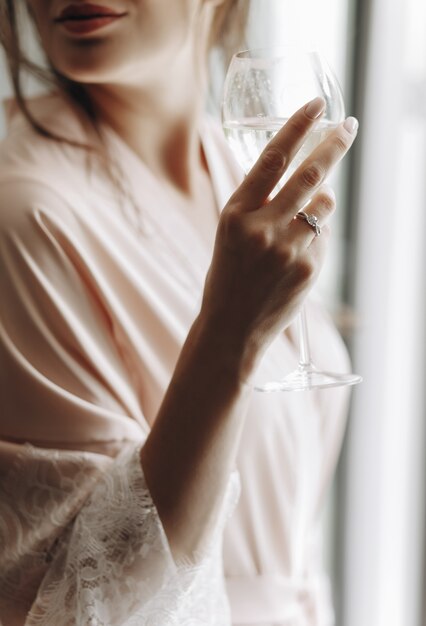 Bride's morning. Seductive bride drinks white wine standing befo