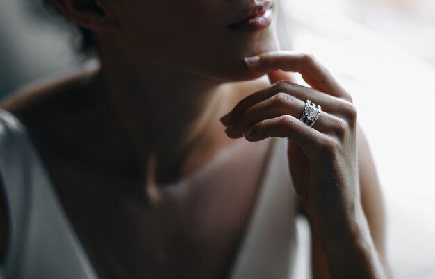 Bride's tender fingers touch her chin