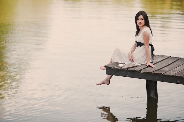 Foto gratuita sposa che si siede nel porto di un lago