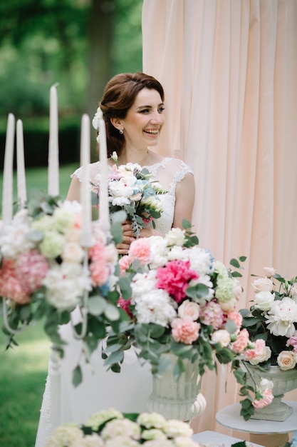 Bride smells wedding bouquet standing before flowerpots