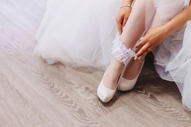 The bride wears shoes on a wedding morning