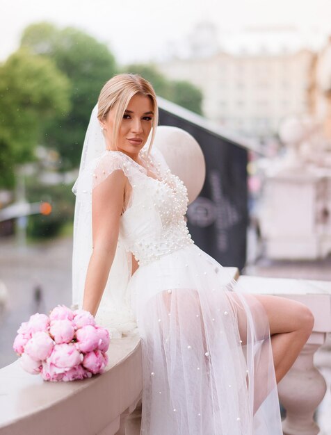 Невеста в свадебном пеньюаре позирует на балконе
