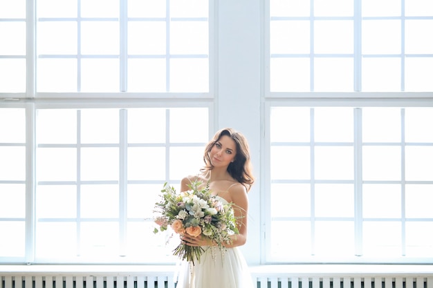 Невеста в белом платье держит букет цветов
