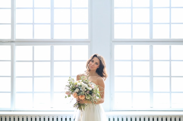 Sposa in abito bianco che tiene un mazzo di fiori