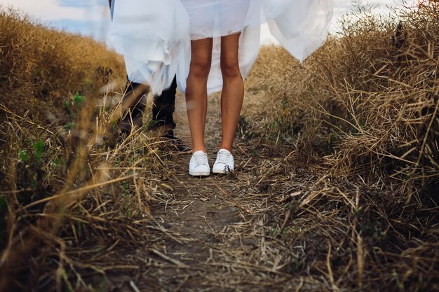 Bride in white kedds stands on the field