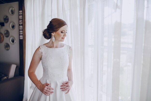 Bride in the window with curtains