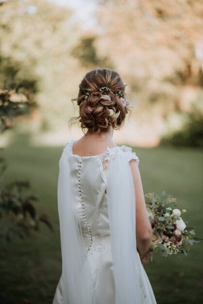 bride with a bridal hairstyle wearing wedding dress holding a flower bouquet