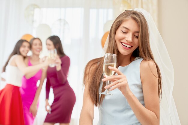 Bride with glass sitting on party in morning