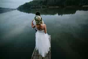 Foto gratuita sposa con il marito di fronte alla ricerca in un lago