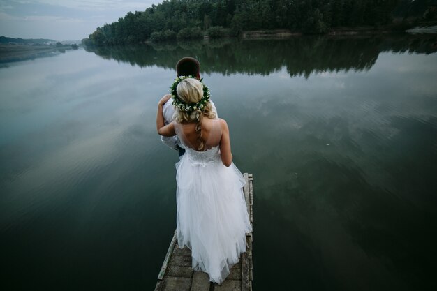 Bride with her husband in front looking at a lake