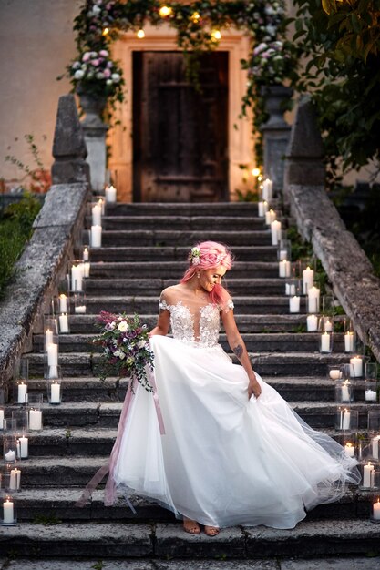 彼女の柔らかい肩の上にピンクの髪と入れ墨が付いている花嫁は光沢のあるろうそくで足音に立っている