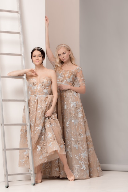 Brides in beautiful dress standing indoors in white studio interior like at home.