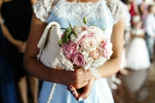 Bridesmaid in blue dress holds pink wedding bouquet 