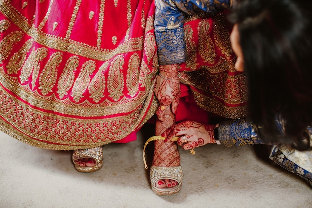 Foto gratuita damigella d'onore aiuta a indossare scarpe sposa indiana