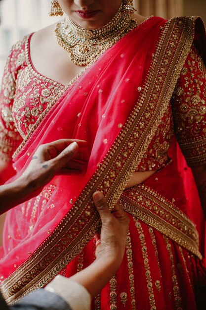 신부 들러리 전통적인 인도 신부 드레스를 입는 데 도움이