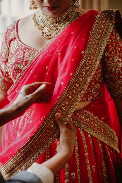 花嫁介添人は、伝統的なインドの花嫁のドレスを着るのに役立ちます