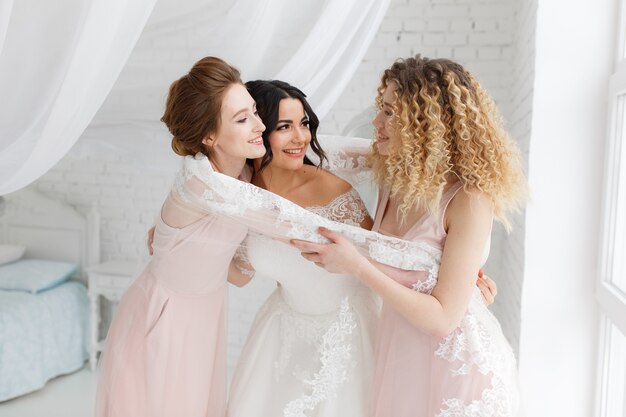 bridesmaid hugging the bride in the bedroom in the morning.