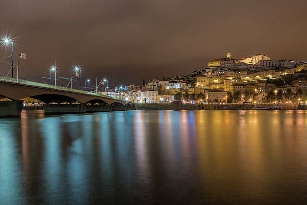 Bridge on the sea in Coimbra with the lights reflecting on the water during the night in Portugal