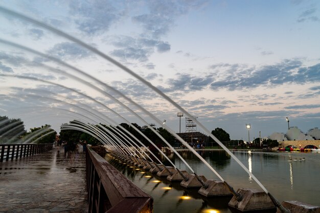 Мост с фонтаном в парке aspire во время драматического заката в дохе, катар