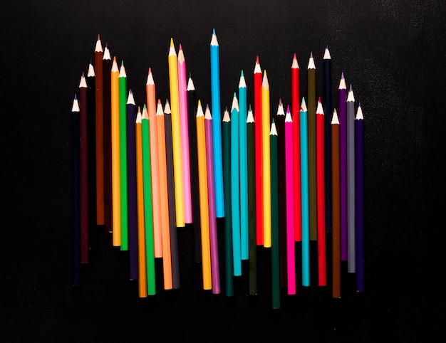 Bright color pencils placed on black background