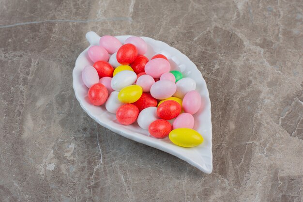 Bright colorful Jellybeans in red, green, pink, blue, yellow and white colors. In white plate.