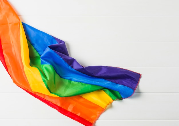Bright crumpled LGBT flag on wooden board 