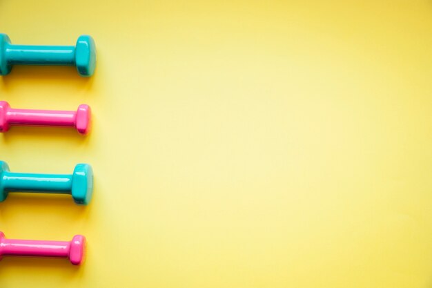 Bright dumbbells on yellow background