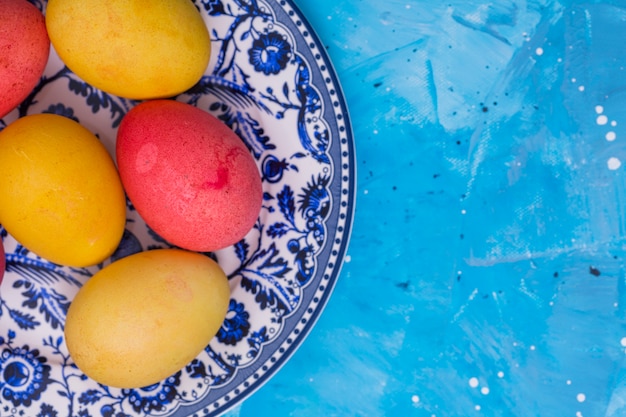 Free photo bright easter eggs on plate on table