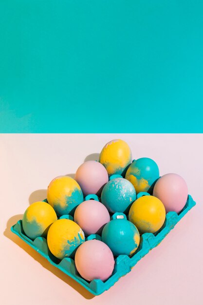 Bright Easter eggs in rack on pink table