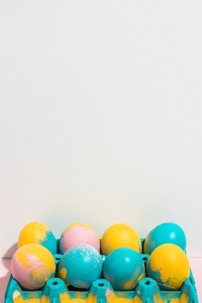 Bright Easter eggs in rack on table 