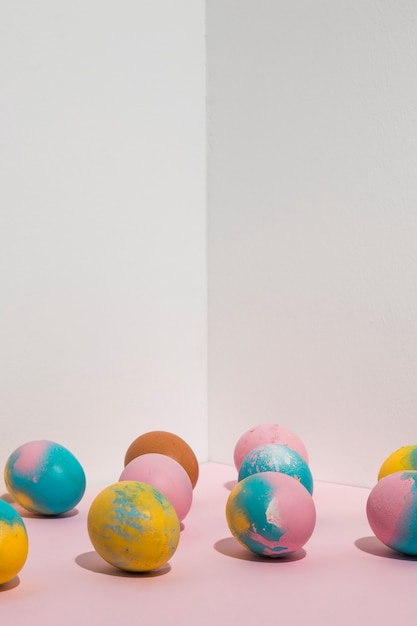 Free photo bright easter eggs scattered on pink table