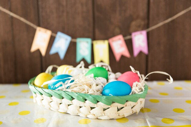 Bright eggs in basket on table