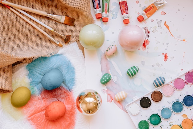 Bright eggs and paints on table