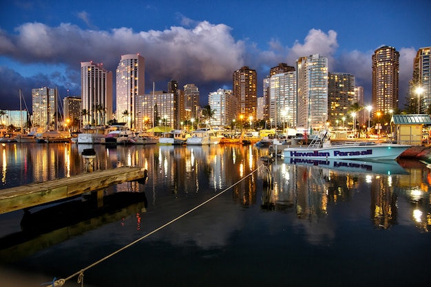 Bright evening lights shine in the windows of skyscrapers over the river