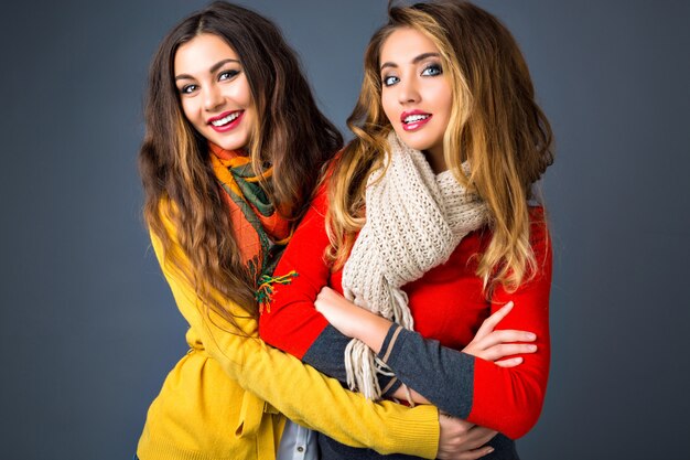 밝은 색상 매트 세련된 스웨터와 스카프를 입고 두 예쁜 금발 머리와 갈색 머리 여자의 밝은 패션 가을 겨울 초상화