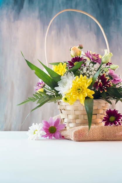 Free photo bright flowers in basket placed on piece of burlap