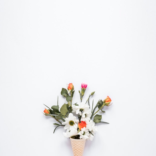 Bright flowers in waffle cone on table