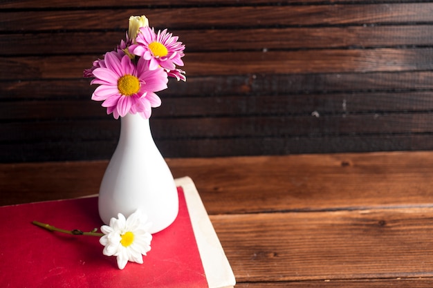 Free photo bright flowers in white vase on book