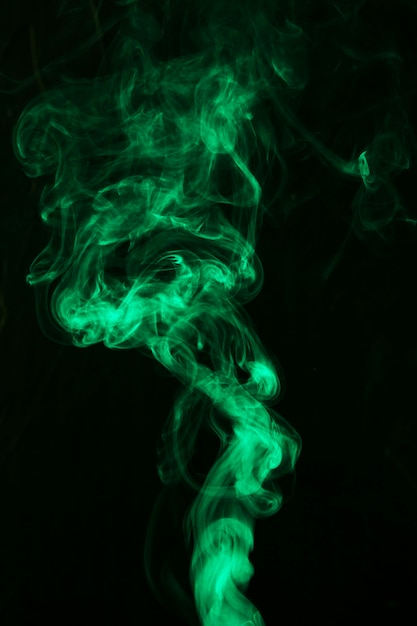 黒の背景に明るい緑の煙