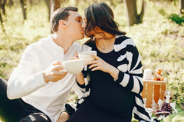 яркая и счастливая беременная женщина, сидящая в парке с мужем и пить чай