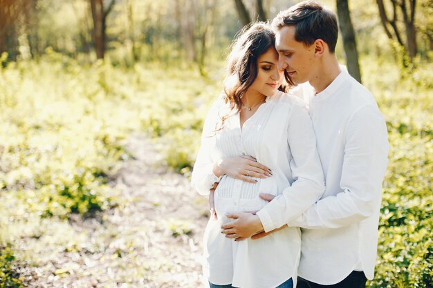 彼女の夫と一緒に公園で歩く明るく幸せな妊娠中の女性