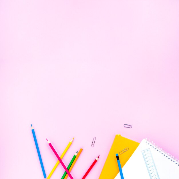 Bright pencils and notebooks laid in random way