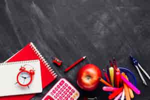 Foto gratuita rifornimenti di scuola rosso brillante e apple sulla lavagna